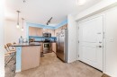 Kitchen featuring wood cabinetry, stainless steel appliances, and an island with pendant lighting - 113 11441 Ellerslie Road, Edmonton, AB  - Indoor Photo Showing Kitchen 