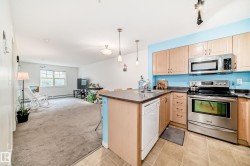Kitchen featuring stainless steel appliances, light wood-finish cabinetry, a double basin sink, solid surface countertops, and pendant lighting - 