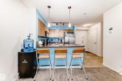 Kitchen area featuring a breakfast bar with pendant lighting, wood-finish cabinetry, stainless steel appliances, and a tile floor - 