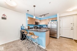 Kitchen featuring light wood-finish cabinetry, stainless steel appliances, a breakfast bar, and pendant lighting - 