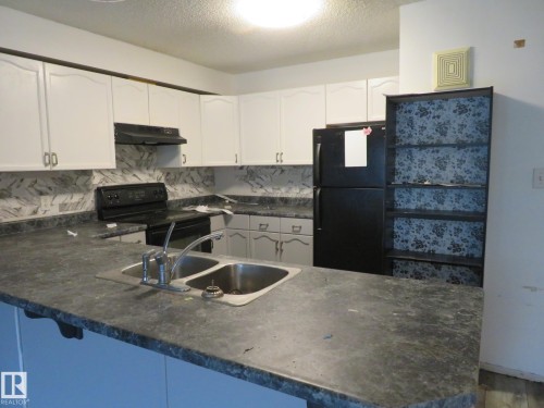Kitchen featuring white cabinetry, a black appliance suite, and a double basin stainless steel sink - 2945 26 Street, Edmonton, AB - Indoor Photo Showing Kitchen With Double Sink