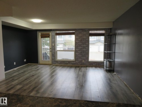 Spacious interior featuring wood-finish flooring, a contemporary ceiling light fixture, and an accent wall with a brick-patterned finish - 2945 26 Street, Edmonton, AB - Indoor Photo Showing Other Room