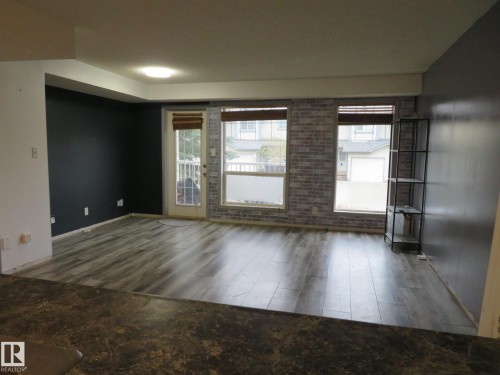 Spacious living area featuring wood-finish flooring, accent walls, and multiple windows for natural illumination - 2945 26 Street, Edmonton, AB - Indoor Photo Showing Other Room