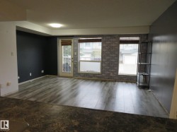 Spacious living area featuring wood-finish flooring, accent walls, and multiple windows for natural illumination - 