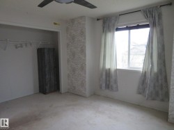 Room featuring a ceiling fan with light fixture, window with curtains, and an open closet with built-in shelving - 