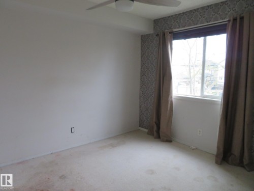 Room featuring a single window, a ceiling fan, and patterned wallpaper accent wall - 2945 26 Street, Edmonton, AB - Indoor