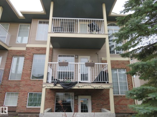 Building exterior featuring multi-level balconies with white railings, a brick facade, and tan siding - 2945 26 Street, Edmonton, AB - Outdoor With Balcony With Exterior