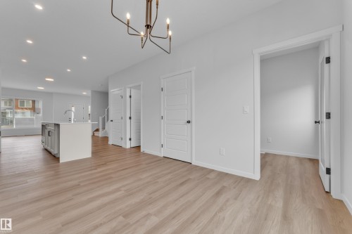 Bright interior featuring wood-finish flooring, recessed lighting, and a contemporary chandelier - 17330 6A Street Ne, Edmonton, AB - Indoor