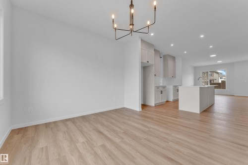 Open-concept living space featuring wood-finish flooring, a contemporary chandelier, recessed lighting, and a kitchen island with an integrated sink and gooseneck faucet - 17330 6A Street Ne, Edmonton, AB - Indoor