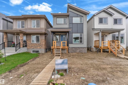 Contemporary-style home featuring a multi-toned facade with vertical and horizontal siding, stone veneer accents, and a distinctive sloped roofline - 17330 6A Street Ne, Edmonton, AB - Outdoor With Facade