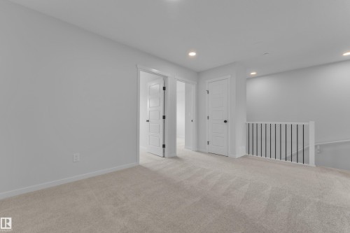 Open upper-level space featuring light-toned carpeting, recessed ceiling lighting, and white walls - 17330 6A Street Ne, Edmonton, AB - Indoor Photo Showing Other Room