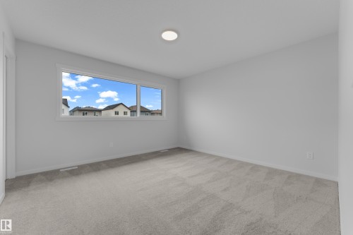 Spacious room with light gray carpeting, neutral wall finishes, and a large window providing natural illumination - 17330 6A Street Ne, Edmonton, AB - Indoor Photo Showing Other Room