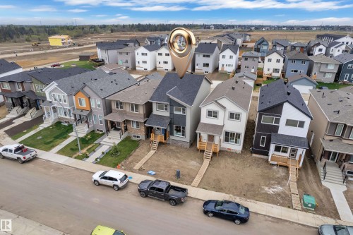 New construction home featuring a two-story design with a light-colored exterior, dark roof shingles, and a visible front porch with natural wood stairs - 17330 6A Street Ne, Edmonton, AB - Outdoor With View