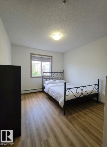 Room featuring wood-finish flooring, a window with a neutral blind, and a ceiling-mounted light fixture - 210 5005 165 Avenue, Edmonton, AB - Indoor Photo Showing Bedroom