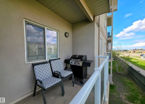 Private balcony featuring a stucco exterior, white window frame, and a glass-paneled railing - 210 5005 165 Avenue, Edmonton, AB - Outdoor With Exterior