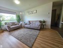 Bright room featuring wood-finish flooring, a large window, white walls, and a flush-mount ceiling light - 210 5005 165 Avenue, Edmonton, AB  - Indoor Photo Showing Living Room 