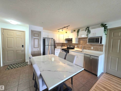 Open-concept kitchen and dining area featuring a spacious dining table with a marble-look top - 210 5005 165 Avenue, Edmonton, AB - Indoor Photo Showing Other Room