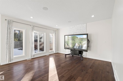 Spacious room featuring dark wood-finish flooring, recessed lighting, and white walls - 2036 Ainslie Link Link, Edmonton, AB - Indoor Photo Showing Living Room