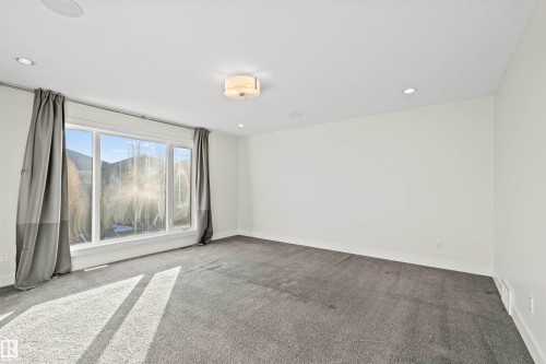Spacious room featuring multiple recessed ceiling lights, a central flush-mount light fixture, and broad windows with white trim - 2036 Ainslie Link Link, Edmonton, AB - Indoor Photo Showing Other Room