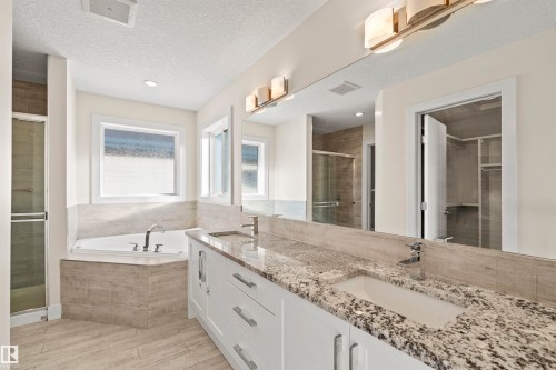 Bathroom featuring a double vanity with stone countertops, an undermount sink, and contemporary fixtures - 2036 Ainslie Link Link, Edmonton, AB - Indoor Photo Showing Bathroom
