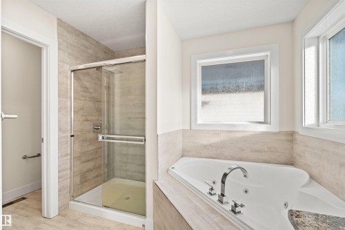 Bathroom featuring a corner jetted soaking tub, a tiled walk-in shower with a glass enclosure, and a chrome faucet set - 2036 Ainslie Link Link, Edmonton, AB - Indoor Photo Showing Bathroom