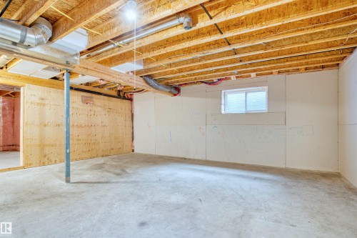 Unfinished basement featuring exposed wood joists, concrete flooring, a single window, and visible HVAC ductwork - 2036 Ainslie Link Link, Edmonton, AB - Indoor Photo Showing Basement