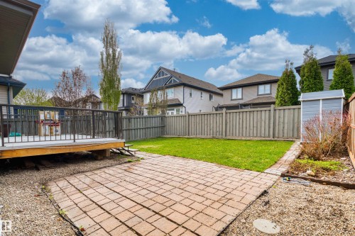 Expansive backyard featuring a wood deck with black railings, a paver patio, a manicured lawn, and a storage shed - 2036 Ainslie Link Link, Edmonton, AB - Outdoor