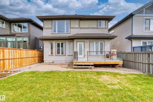 Expansive backyard featuring a manicured lawn, a paver patio area, and a wood deck with metal railings - 2036 Ainslie Link Link, Edmonton, AB - Outdoor With Deck Patio Veranda