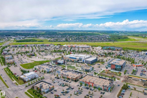Aerial perspective showcasing a commercial district with multiple retail and office buildings, extensive paved parking areas, and mature landscaping - 2036 Ainslie Link Link, Edmonton, AB - Outdoor With View