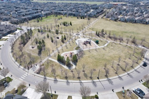 Central park space featuring a circular road, pedestrian pathways, mature trees, and a play area - 2036 Ainslie Link Link, Edmonton, AB - Outdoor With View