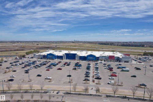 Large retail building with a prominent blue facade and extensive parking lot - 2036 Ainslie Link Link, Edmonton, AB - Outdoor With View