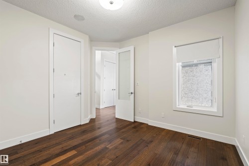 Room featuring wood-finish flooring, white baseboards, and a window with a roller shade - 2036 Ainslie Link Link, Edmonton, AB - Indoor Photo Showing Other Room