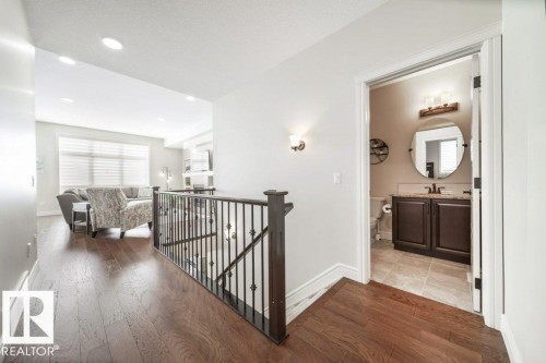 Upper-level landing with dark wood-finish flooring and wrought iron railing - 3 8050 Orchards Green, Edmonton, AB - Indoor Photo Showing Other Room