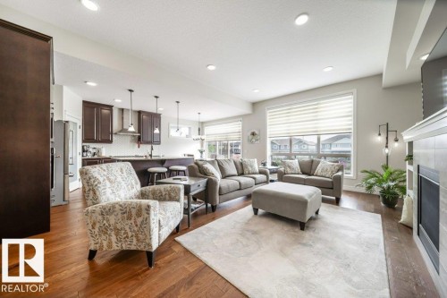 Open-concept living area with wood-finish flooring - 3 8050 Orchards Green, Edmonton, AB - Indoor Photo Showing Living Room With Fireplace