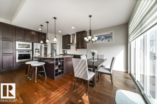 Open-concept kitchen and dining area featuring rich wood-finish flooring - 3 8050 Orchards Green, Edmonton, AB - Indoor