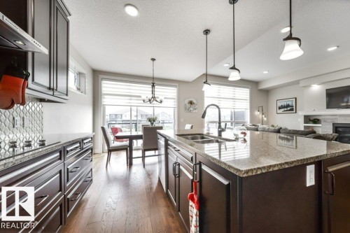 Kitchen island featuring a double basin sink and a stone countertop - 3 8050 Orchards Green, Edmonton, AB - Indoor Photo Showing Kitchen With Double Sink With Upgraded Kitchen