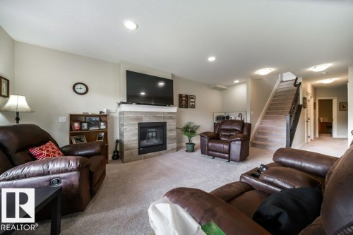Living area featuring a tiled fireplace with a mantel, recessed lighting, and carpeted flooring - 3 8050 Orchards Green, Edmonton, AB - Indoor Photo Showing Living Room With Fireplace