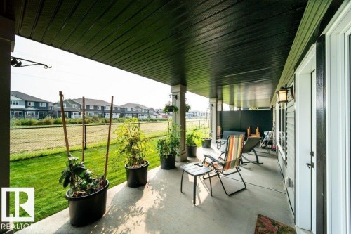Covered concrete patio featuring a dark soffit and multiple support pillars - 3 8050 Orchards Green, Edmonton, AB - Outdoor With Deck Patio Veranda With Exterior
