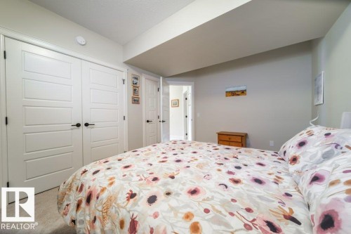 Bedroom featuring neutral wall colors, carpet flooring, and white paneled doors with black hardware - 3 8050 Orchards Green, Edmonton, AB - Indoor Photo Showing Bedroom