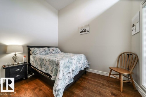 Bedroom featuring wood-finish flooring, white baseboards, and a light-colored wall finish - 3 8050 Orchards Green, Edmonton, AB - Indoor Photo Showing Bedroom