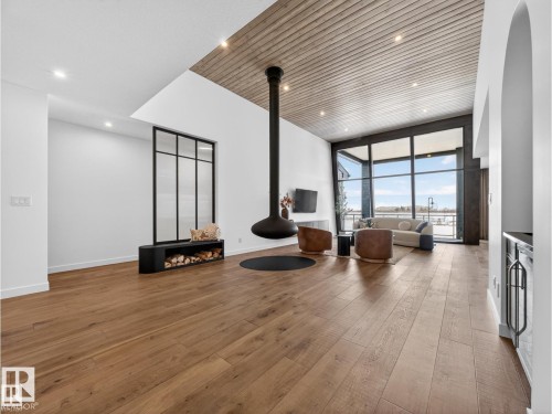 Vaulted ceiling with wood paneling, featuring a suspended fireplace with hearth, and wide-plank wood-finish flooring throughout - 7104 54 Avenue, Beaumont, AB - Indoor Photo Showing Other Room