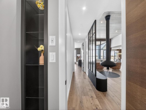 Hallway featuring wood-finish flooring, a built-in shelving unit, and a contemporary suspended fireplace - 7104 54 Avenue, Beaumont, AB - Indoor Photo Showing Other Room