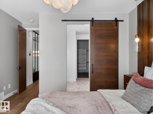 Wood-finish barn door entry featuring a black hardware track - 7104 54 Avenue, Beaumont, AB - Indoor Photo Showing Bedroom