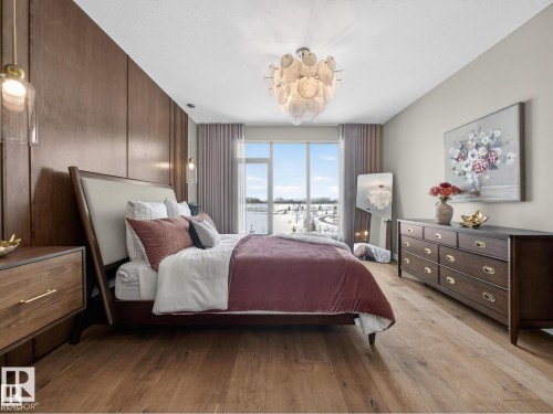 Wide plank wood-finish flooring complements the wood-paneled accent wall - 7104 54 Avenue, Beaumont, AB - Indoor Photo Showing Bedroom