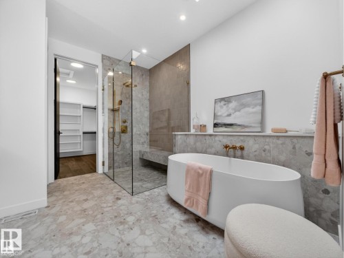 Spacious bathroom featuring a freestanding soaking tub, a frameless glass shower enclosure, and large format terrazzo-style floor tile - 7104 54 Avenue, Beaumont, AB - Indoor Photo Showing Bathroom