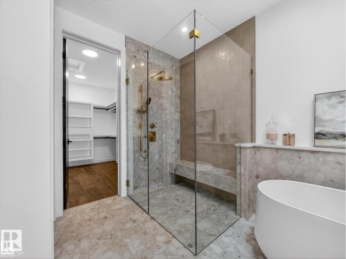 Expansive glass-enclosed shower with gold-tone fixtures and a built-in bench - 7104 54 Avenue, Beaumont, AB - Indoor Photo Showing Bathroom