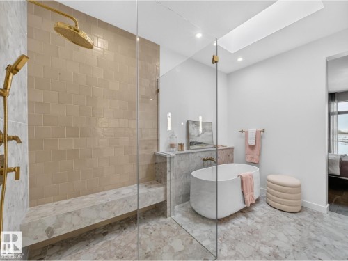 Spacious bathroom featuring a frameless glass shower enclosure, a built-in shower bench, and gold-finish shower fixtures - 7104 54 Avenue, Beaumont, AB - Indoor Photo Showing Bathroom