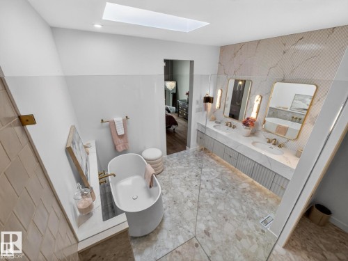 Contemporary bathroom featuring a freestanding tub, dual vanity with undermount sinks, and a skylight - 7104 54 Avenue, Beaumont, AB - Indoor