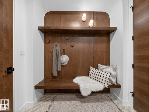 Built-in wood-finish mudroom bench with upper shelf and integrated wall hooks - 7104 54 Avenue, Beaumont, AB - Indoor Photo Showing Other Room
