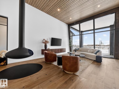 Living area featuring a suspended matte black fireplace and wide plank wood-finish flooring - 7104 54 Avenue, Beaumont, AB - Indoor